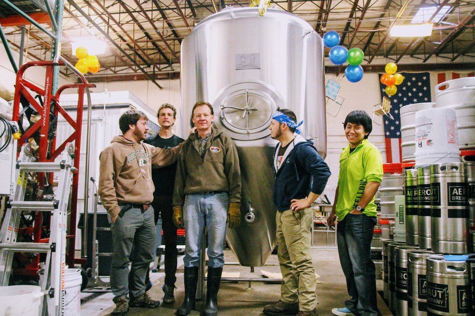 Aeronaut Cannery staff stands in front of a stainless steel fermenter