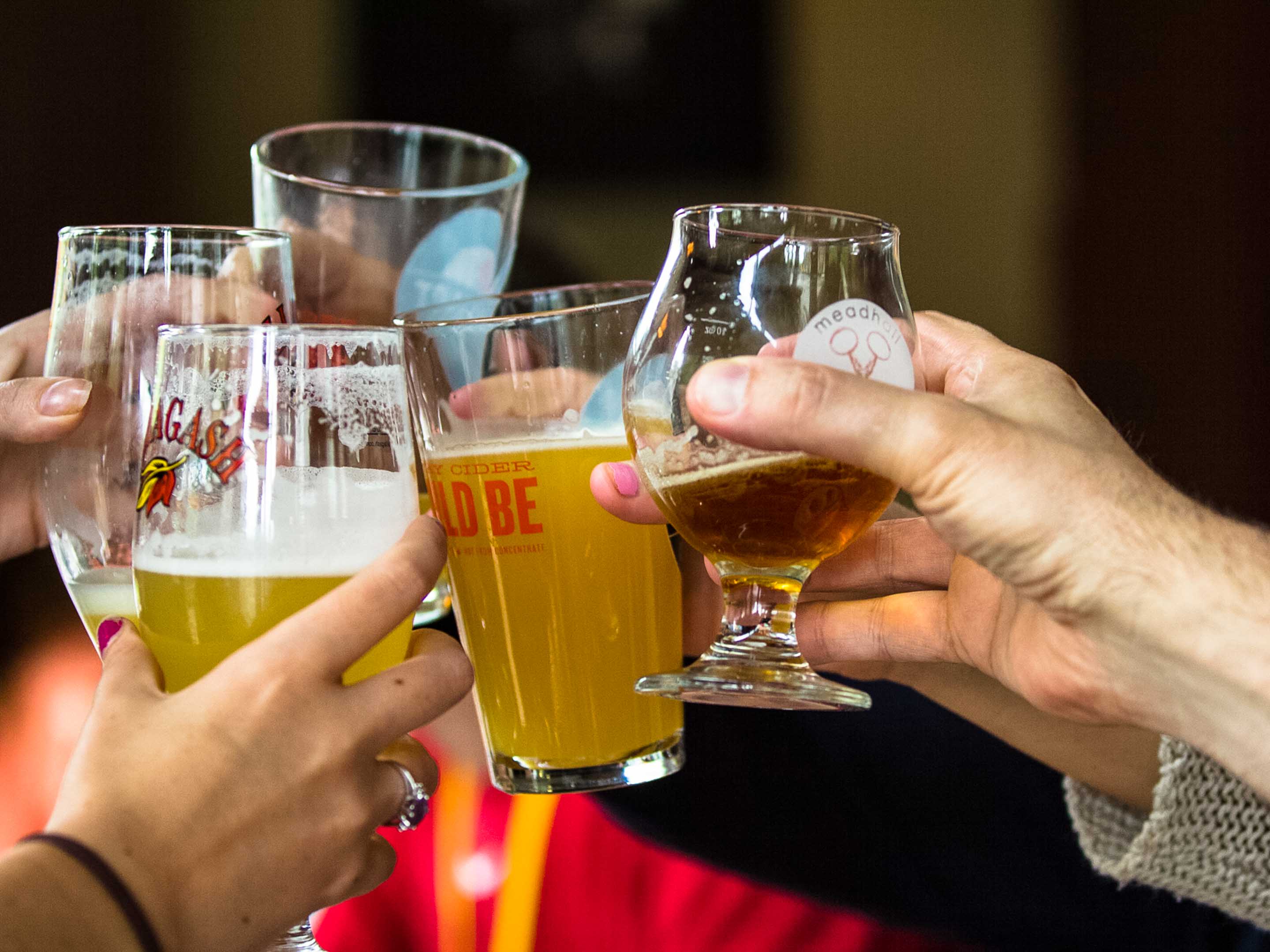 A close up of beer glasses coming together in a toast