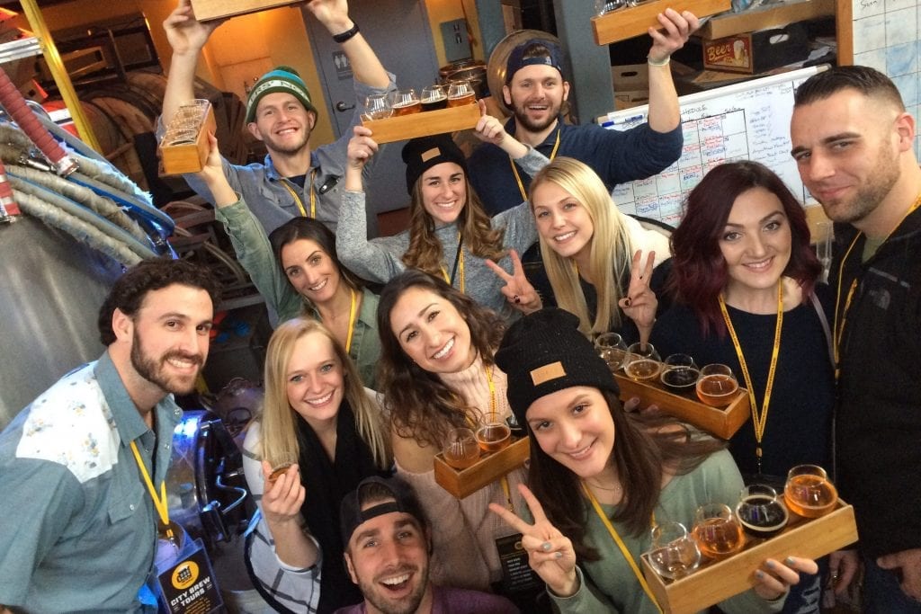 A private tour group poses for a picture with flights of beer