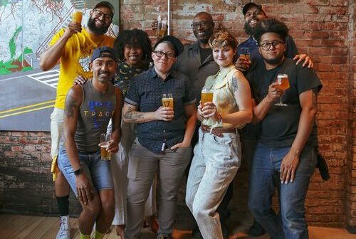 A photo of Trace Brewing staff members posing with beer.